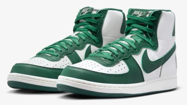Side view of white and green Nike shoes.